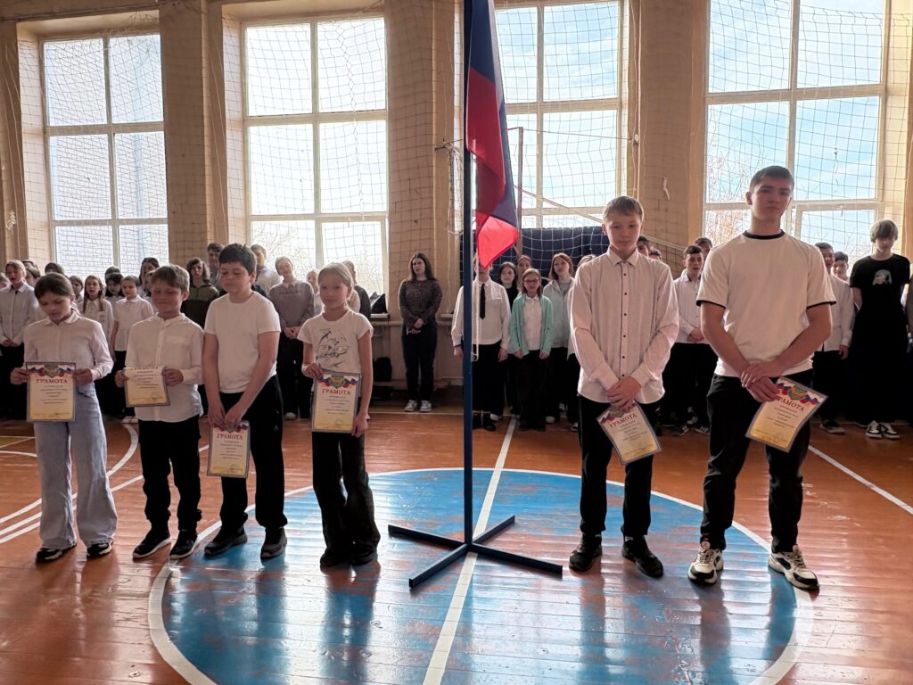 Ребята с грамотами стоят на поднятии флага