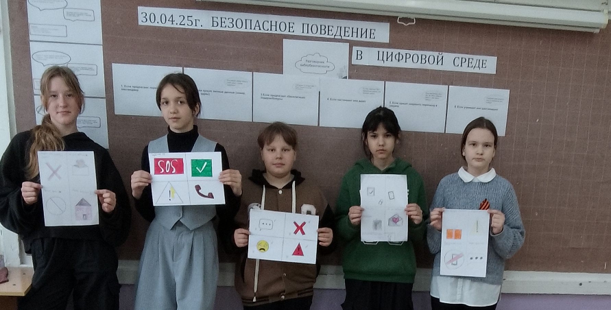 Обучающиеся 5а класса показывают памятки по цифровой безопасности, изготовленные своими руками