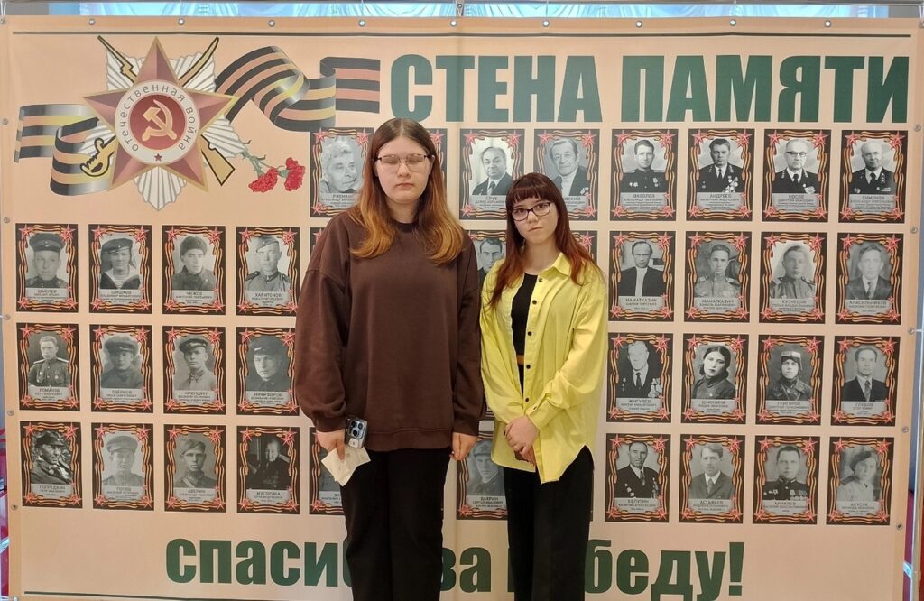 Ученицы стоят у Стены Памяти