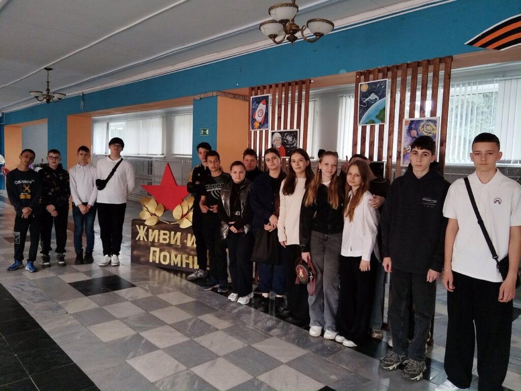 Ребята 8 А и 8 Б класса стоят около выставки рисунков посвященных дню космонавтики