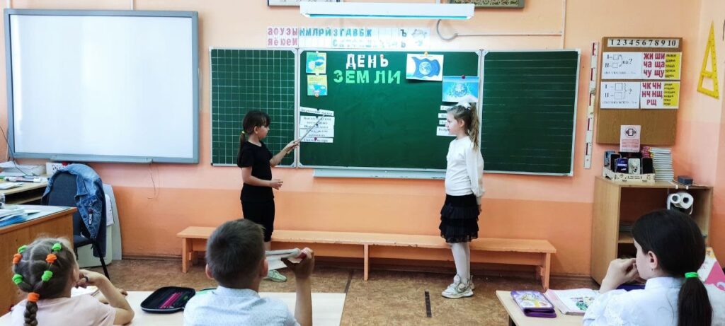 Ученики стоят у доски и показывают на картинки Земли