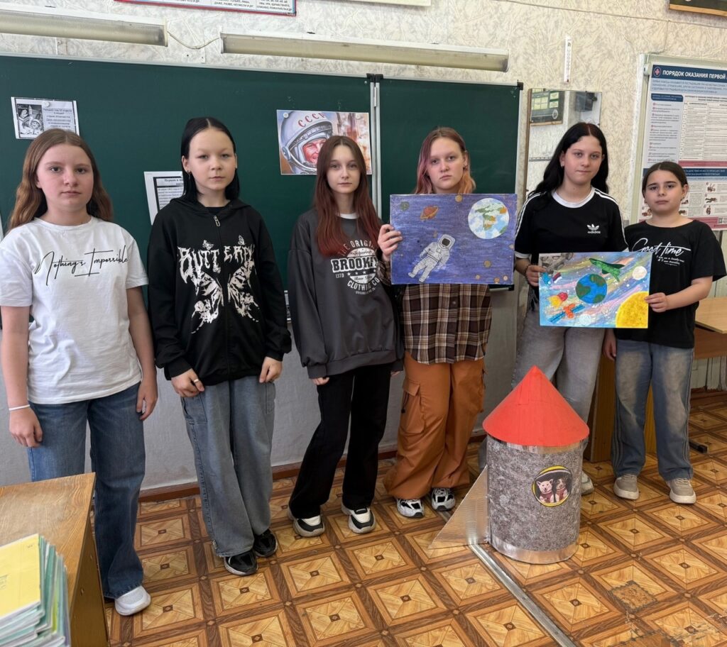 Ребята стоят у доски и держат свои рисунки ко дню Космонавтики