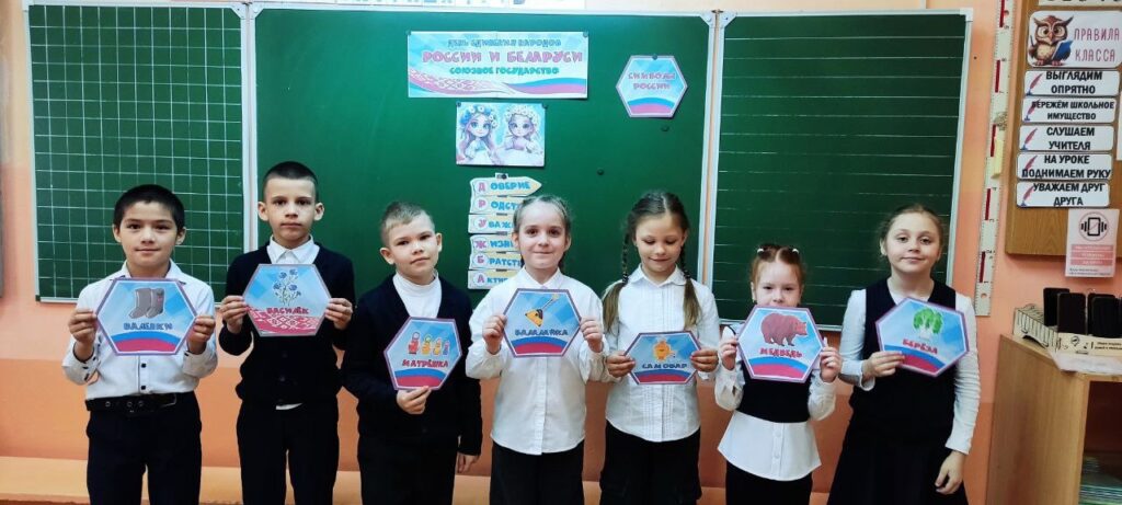 Ребята стоят у доски, держат в руках символы России и Белорусии