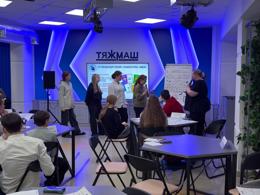 Девочки стоят у стенда и защищают свой проект