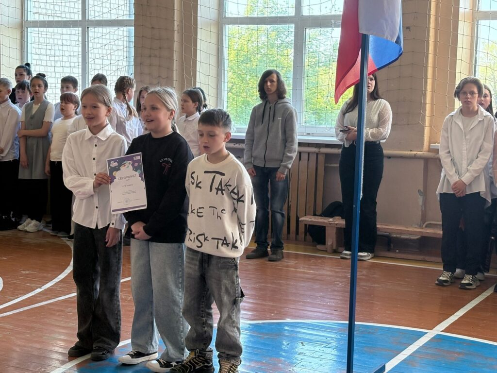 Ребята стоят на поднятии флага и исполняют гимн РФ